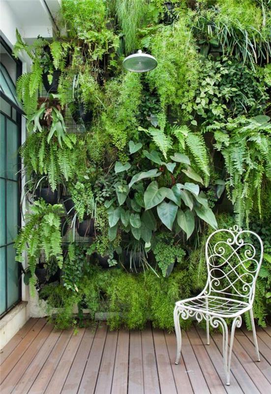veľká zelená rastlinná stena, vonkajší sprchovací kút, biela kovová stolička v retro štýle, podlaha pokrytá svetlo hnedými drevenými trámami, oblečte vonkajšiu stenu