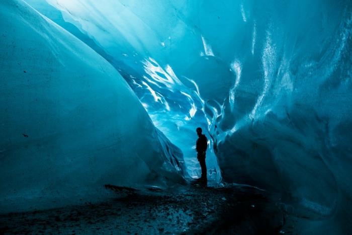 en man i en isgrotta, vackert paradisiskt landskap, atmosfär av lugn och fred, mjukt ljus som lyser upp isen