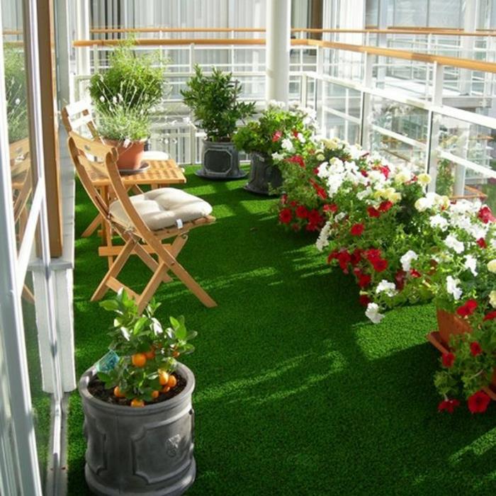 Krásny balkón so syntetickými trávami a zelenými trávnikmi na balkón s drevenými stoličkami