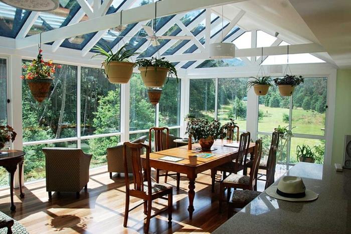 underbar-idé-av-deco-veranda-omvandlad till en matsal-ett-överflöd-av-växter-laminat-golv-utsikt-på-ett-skog-landskap