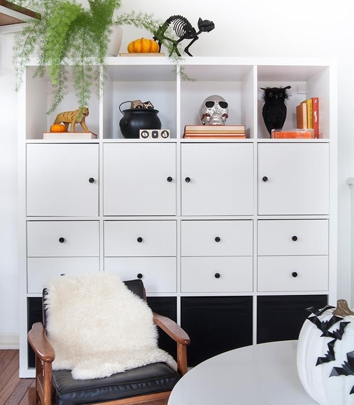 vitt och svart hus halloween deco, rum med vita väggar med trägolv och trämöbler, vit pumpa med svarta pappersfladdermöss
