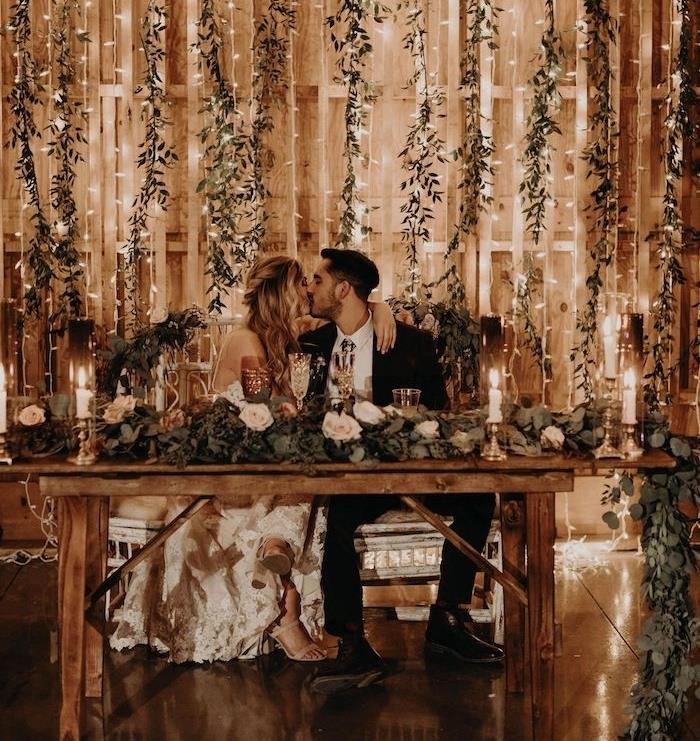 svetlé girlandy a girlandy zo zelených listov na ozdobenie stien starého veľkého, rustikálneho stola, rustikálne elegantné svadobné deko