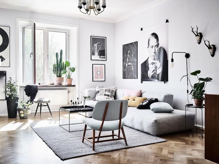 litet skandinaviskt vardagsrum med mysig soffa på golvet, översteget av en vägg av konstnärliga ramar i stort format