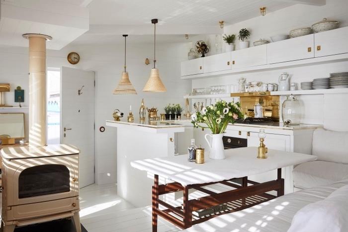 litet kök i chic stil med vit fasad och vit ö, träbord med vit skiva och intilliggande hörnsoffa, vintage spis, blommig inredning