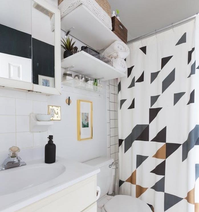 príklad malá kúpeľňa s policami nad toaletou, sprchový záves s geometrickými vzormi, skriňa so vstavaným zrkadlom