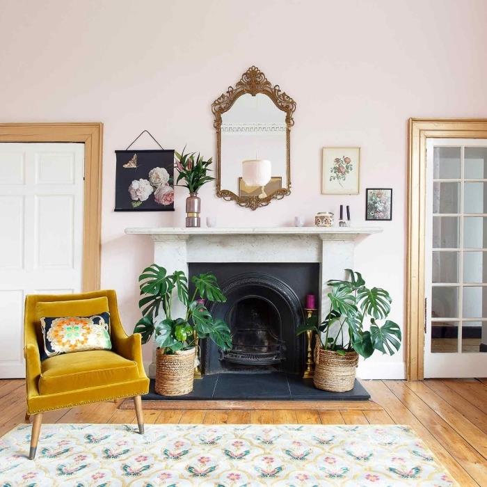 bohémsky dekor so zelenými rastlinami a dreveným nábytkom, nápad na farbu steny do obývačky v pastelovo ružovom modeli kresla z horčicového zamatu