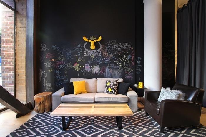 omietka s čiernym kriedovým efektom, výzdoba obývačky s drevenými podlahami a tmavými stenami s bridlicovou textúrou, žlté akcenty v dekore