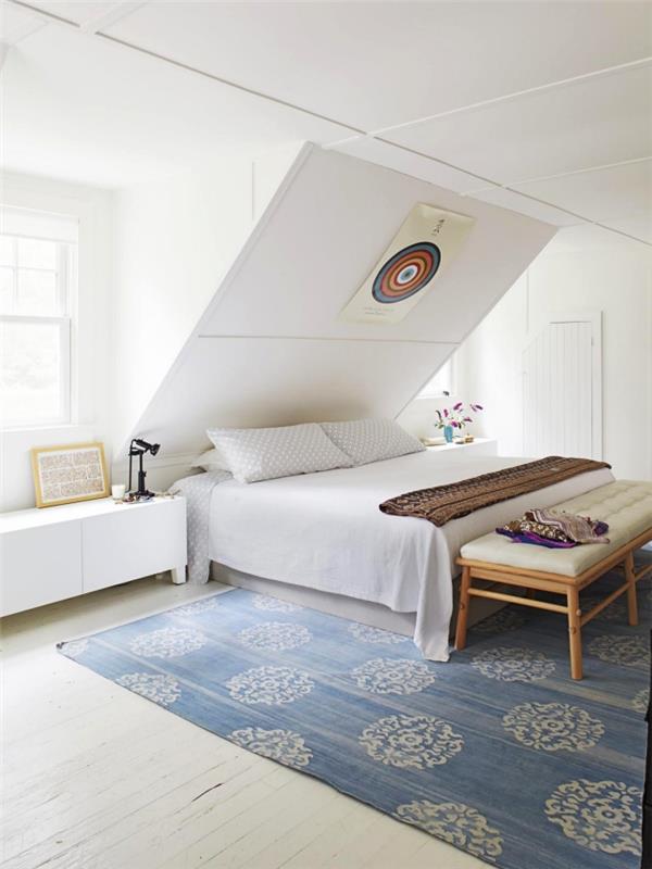 ett monokromatiskt vitt sovrum som är utrustat på vinden med en säng placerad under sluttningen