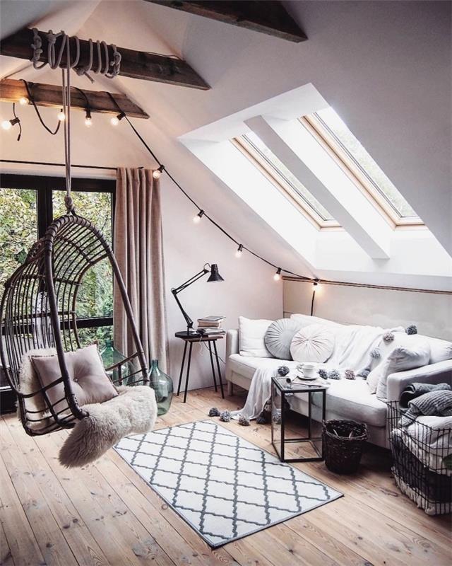 kokongdekoration i vindsrum i skandinavisk stil med en vit soffa under takfönstren och en gunga hängande från träbjälken