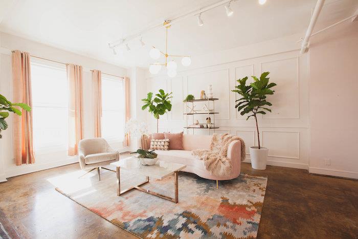 minimalistická výzdoba obývačky s ružovou sedačkou, farebným kobercom, narbovým a kovovým stolom, podlahou s efektom hrdze, bielymi stenami a dekoráciou obývačky