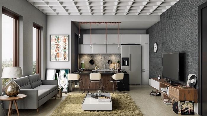 vardagsrum med vita väggar med sektion av grå stenmur och beige golv, utrustad köksmodell med vita möbler