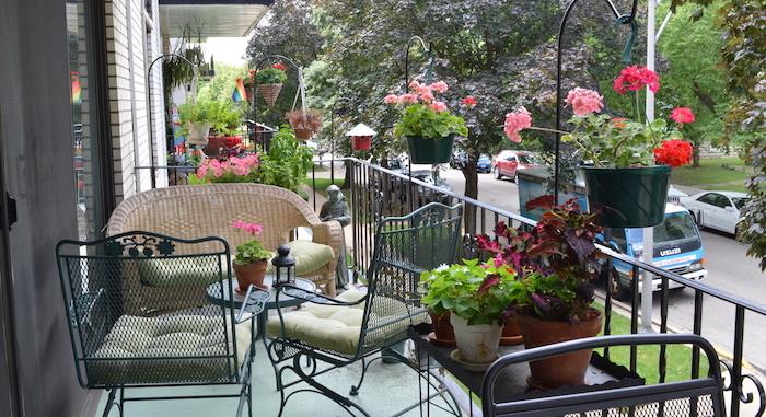 trädgårdsmöbler idé på en balkong med utsikt över en gata, metallstolar och soffbord i metall, rottingsoffa, dekorativ statyett, blommor