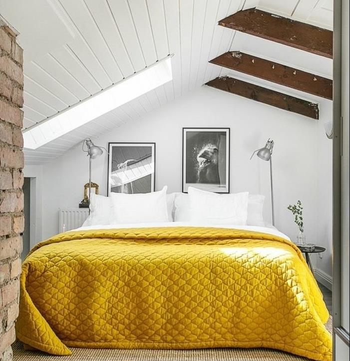 vindsovrum, vit väggfärg, väggdekoration svartvita foton, vita sängkläder, gult sänglinne, synliga balkar, tegelvägg