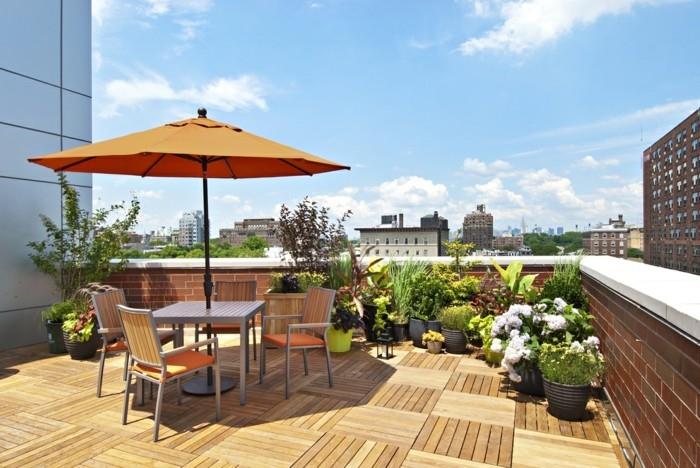 idé för en terrass på taket av en byggnad, träbeklädnad, grått bord och stolar, växter i grå blomkrukor, orange parasoll