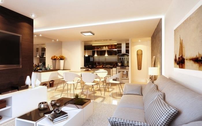 öppet amerikanskt kök i rostfritt stål, vitt bord och stolar, beige klinkergolv, grå soffa och matta, svartvitt soffbord, afrikansk inredning och dekorativt bord