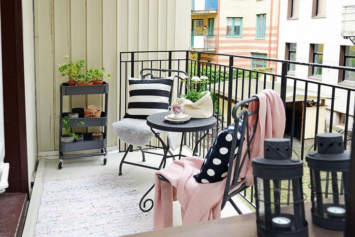 sätta upp en terrass med svart balustrade, kokongmatta, stolar och bord i svart metall, blomsterhylla, svarta lyktor