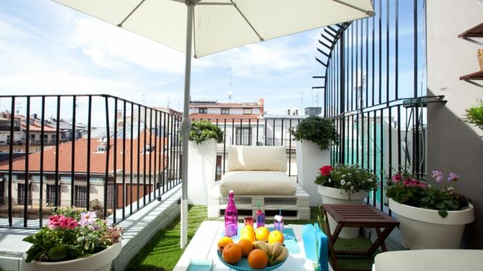 balkong, utemöbler, konstgräsbeklädnad, pallfåtölj med benvitt säte, pall soffbord, flera blomkrukor, vit parasoll
