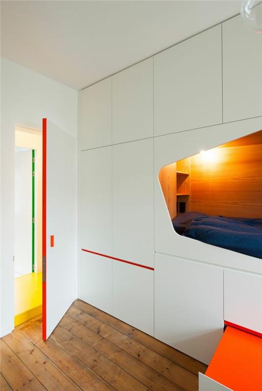 Dispozícia 9m2 malá spálňa s futuristickým výklenkom pre posteľ, červenými a oranžovými farbami, drsnými drevenými podlahami