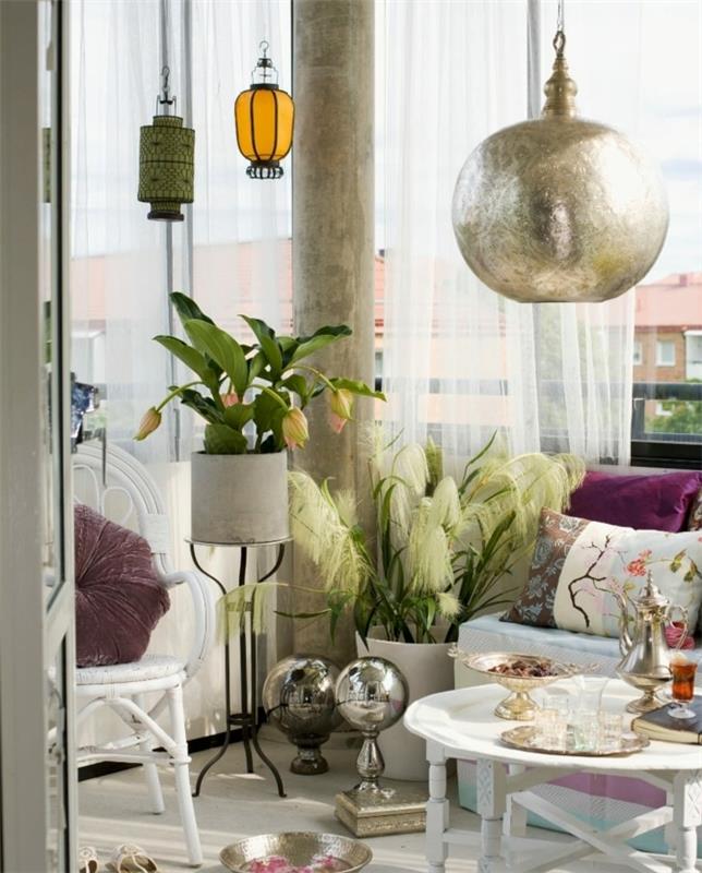 terrassidé med vit soffa, färgglada kuddar, vitt soffbord, designlyktor, orientaliska dekorativa tillbehör, vita stolar, gröna växter