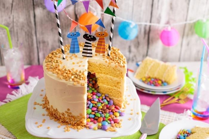 smarties -tårta med flera lager vaniljkakor och smörkrämglasering dekorerad för ett barns födelsedag med en banderoll och kattkakstoppar
