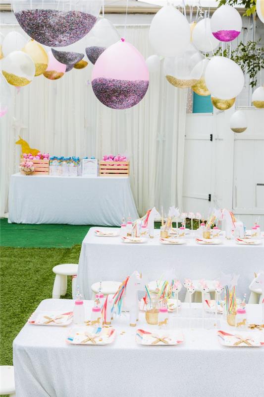 en födelsedagsfest med enhörningstema i rosa, vitt och guld med en ljus dekoration av personliga ballonger med glitter