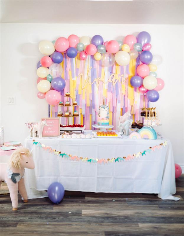 deco -idé för en enhörningsfödelsedag med en vägg av streamers med pastellballonger på gränsen