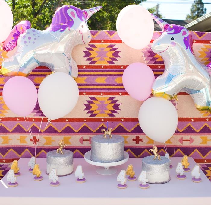 idé för en vacker utomhus enhörning födelsedagsbuffé dekoration med gigantiska aluminiumballonger och färgglada aztekiska mönster som bakgrund