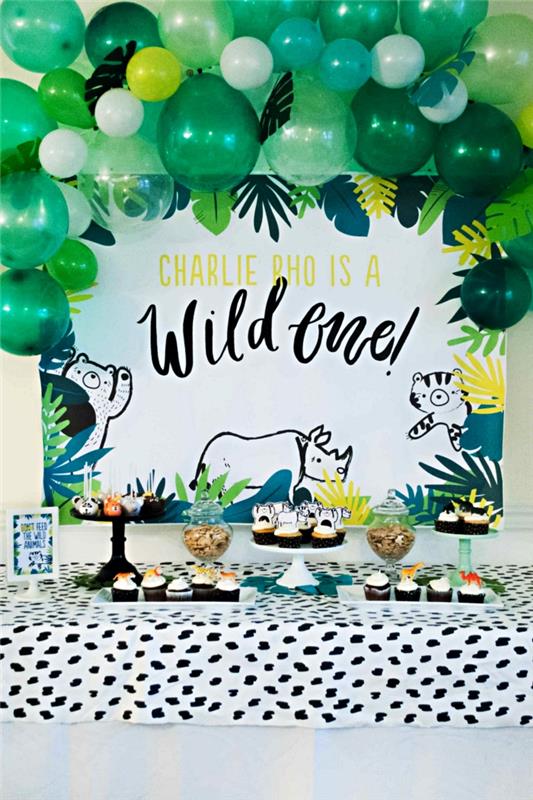 ballongbåge i gröna nyanser och djungelbakgrund för att dekorera en födelsedagsgodis med djungeltema, barnfödelsedagsdekor med tropiskt tema