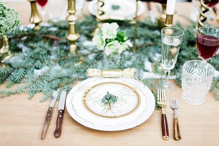 vit och guld tallrik gröna grenar julbord dekoration glasögon trälock guld ljusstakar träbord