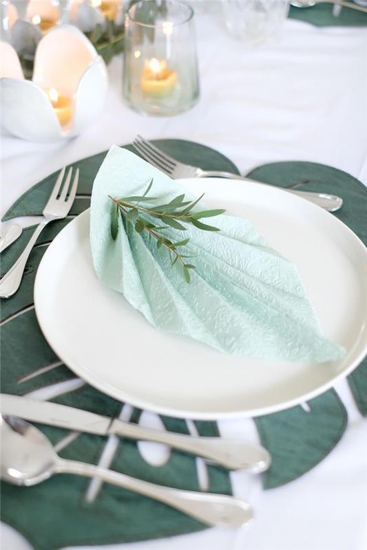 prírodná dekorácia na stôl v bielej a zelenej farbe so striebornými príbormi a sviečkami, myšlienka rýchleho skladacieho papierového obrúska v tvare listu