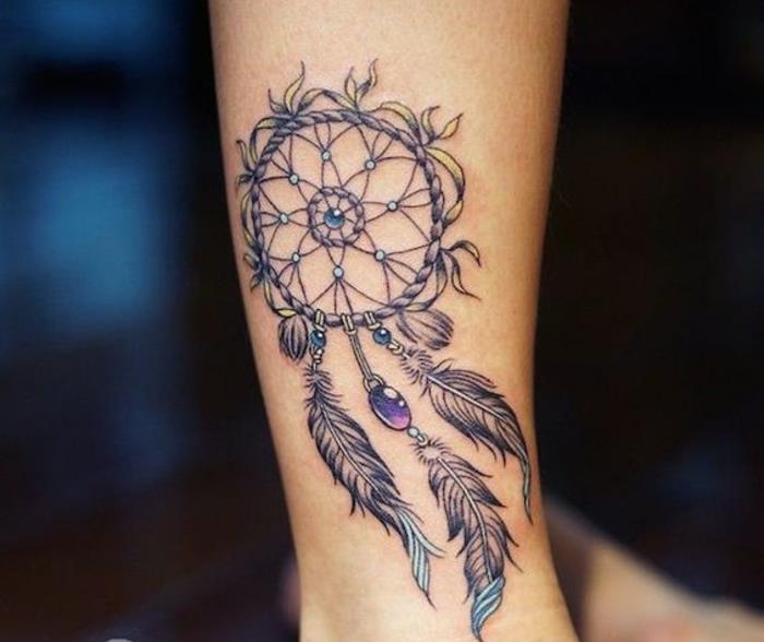 drömfångare tatuering på underarm, rosenät, ring, lila och blå pärlor, grafiska fjädrar med blå ändar