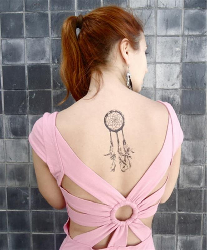 dreamcatcher -tatuering på baksidan, grafiska linjer, ring, nät och fjädrar, rosa klänning, rött hår, fjäderörhängen