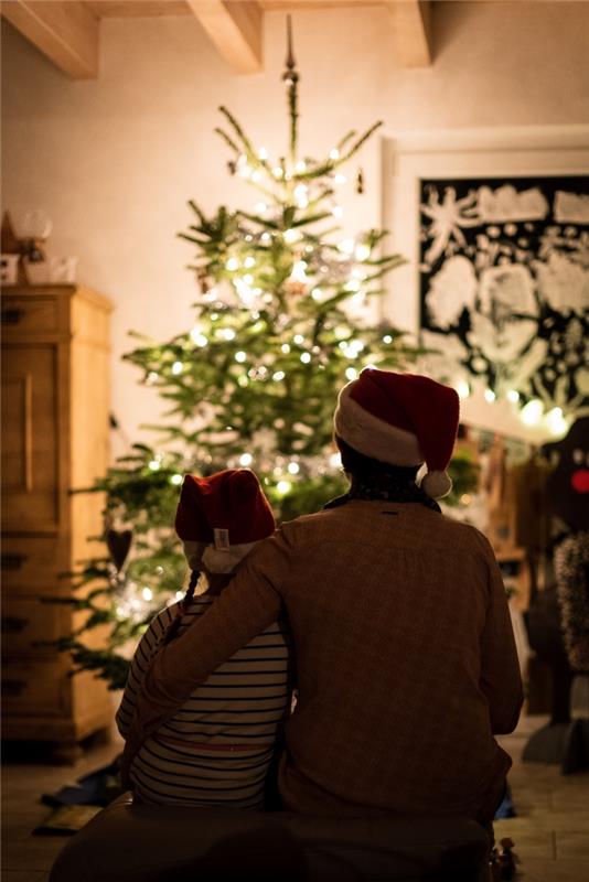 God julbild med barn och hans far framför ett naturligt träd i vardagsrummet, familjefoto för julfoto