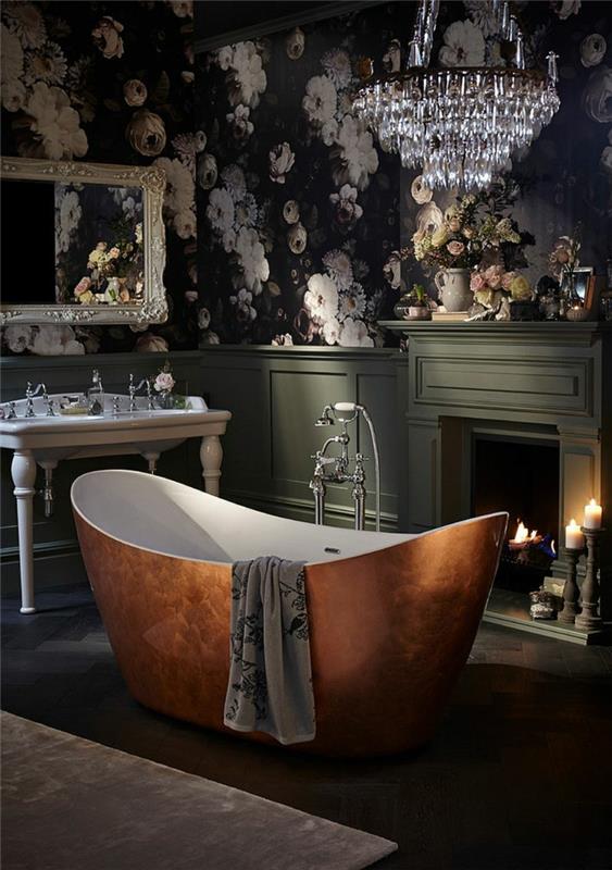 veľká medená vaňa v strede retro kúpeľne, veľké kryštálové stropné svetlo, pozoruhodné umývadlo, čierna tapeta s ružovými kvetmi, zapálené sviečky