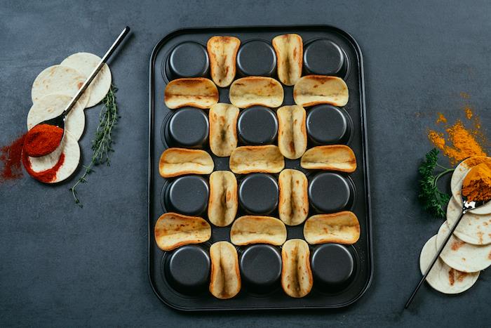 skedar kryddor, hur man gör tacos, tortilla -omslag, arrangerade på en svart, muffinsbricka, svart bord