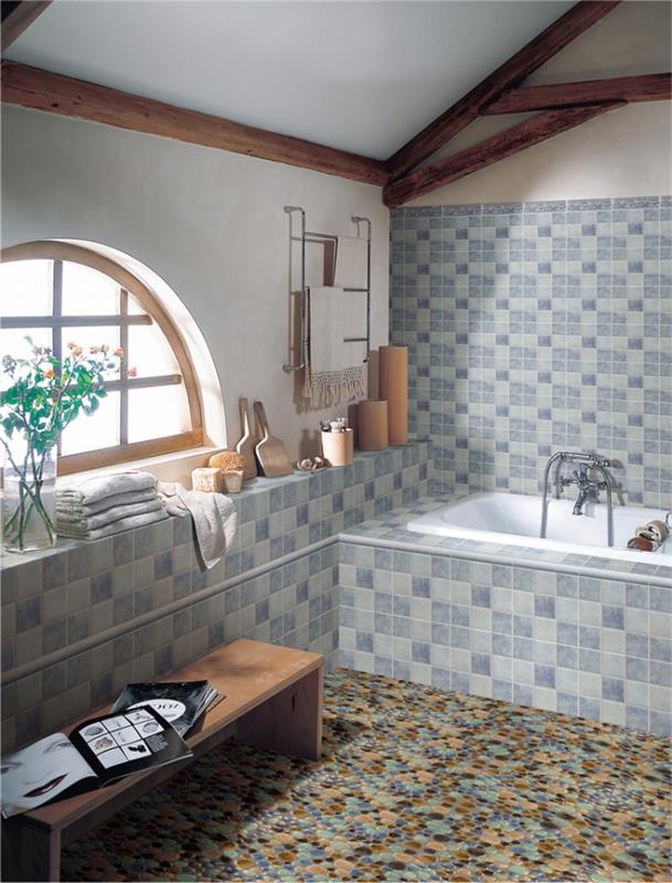 badrumsinredning i rustik stil med geometrisk designplattor i grå och blå färg, liten badkarsmodell