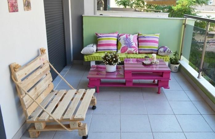 bänk-i-pall-med-hjul-polerad-trä-soffa-i-pall-sittdynor-pistasch-grön-mångfärgade-kuddar-pall-soffbord-målade-i-rosa-trädgård-lounge-pall- på terrassen