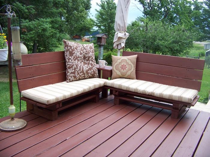 drevená paletová lavica premaľovaná na hnedú s béžovými a hnedými podsedákmi na vonkajšej drevenej terase