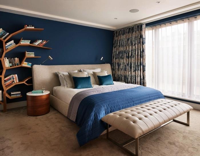 moderný dekor do spálne s polnočnými modrými stenami a bielym stropom s poličkou z tmavého dreva