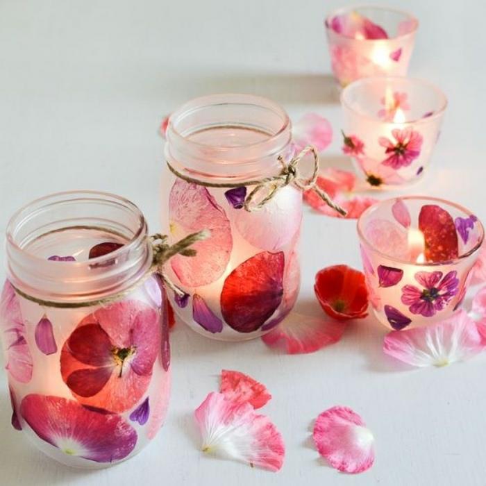 Idee artigianali con dei barattoli di vetro decorati con petali di fiori e utilizzati come portacandele