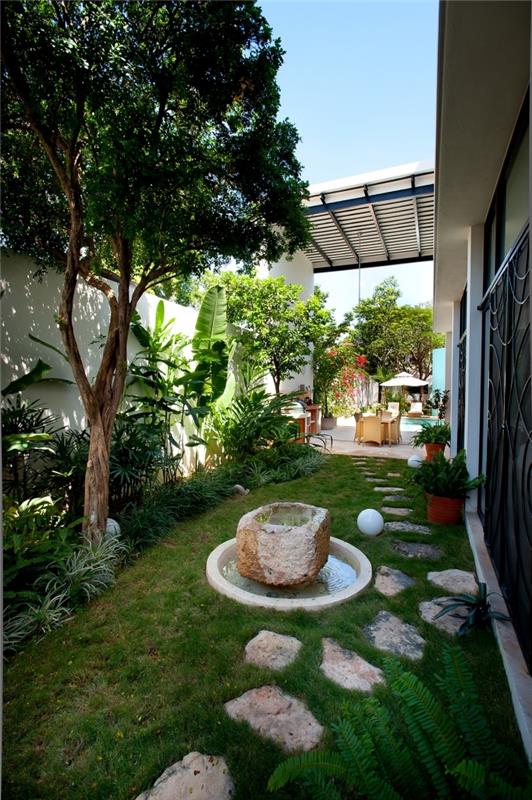 príklad upravenej záhrady s kamennou cestou a malým jazierkom, vonkajšia dekorácia malý priestor s trávou a stromami