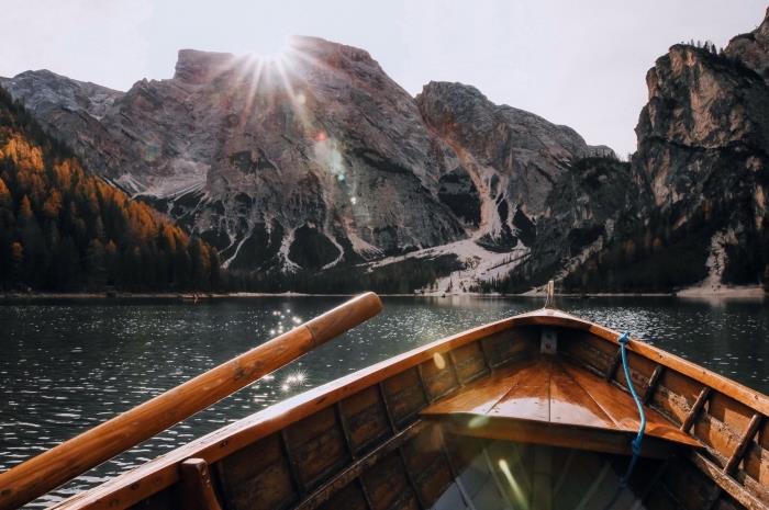 fotografia lode v jazere v srdci hôr, krásna tapeta so slnkom nad skalami