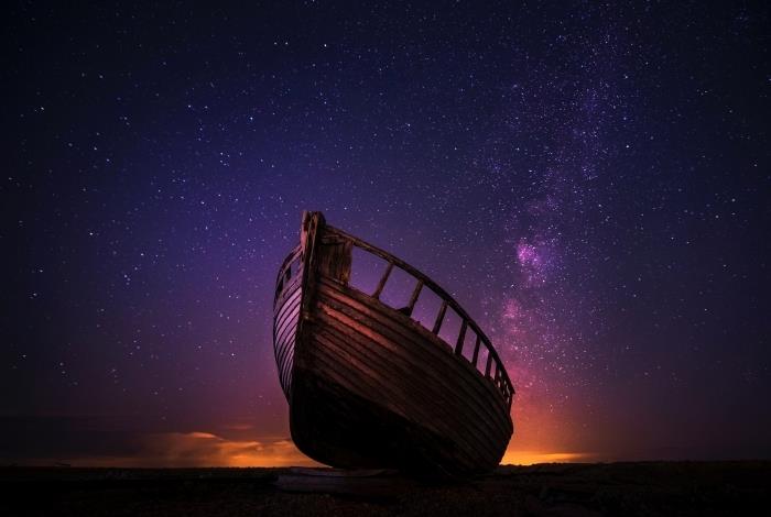 اجمل خلفيات للكمبيوتر صورة مع منظر ليلي خرافي مع سماء بنفسجية مرصعة بالنجوم وقارب خشبي
