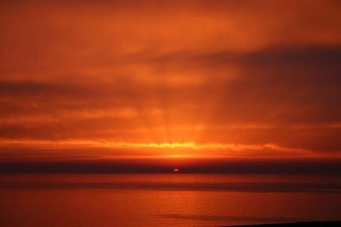 landskap i rött, med strålar som filtrerar genom molnen, lugnt hav, röd solnedgång, nästan overklig atmosfär, fred och zen, total förändring av landskap, himmelska landskap
