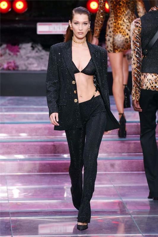 بيلا حديد تسير على المدرج ، مرتدية بدلة سوداء مطرزة ، تتكون من حمالة صدر وسترة ، اتجاهات الموضة الحالية