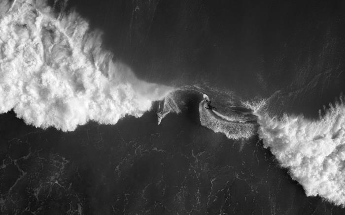 vackert svartvitt foto av surfare och båt i öppet hav i surfarens