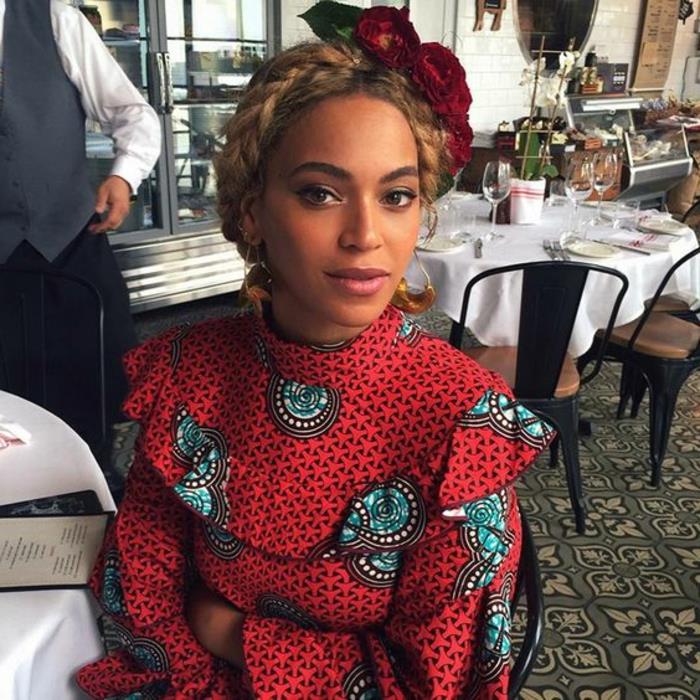 beyonce sitter ner, bär ett ljusare kranshuvudband, afrikanska klänningar, mönstrad topp, flätat hår