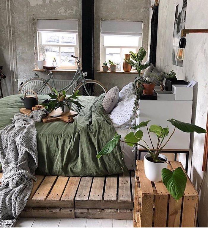 Priemyselný dekor v perfektnej spálni Tumblr, fotka spálne v štýle Tumblr, zelené rastliny, miesto pre bicykle, nenatreté priemyselné steny, nočný stolík a posteľ z paliet