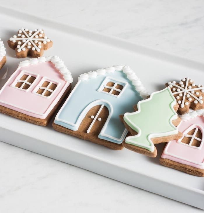 Julkaka i pepparkaksdeg i form av ett hus, julgran och snökolv med färgad glasyr i pastellfärger