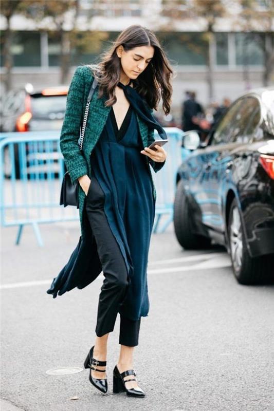 امرأة تمشي في الشارع ، اتجاهات الموضة لعام 2019 ، تنظر إلى هاتفها ، مرتدية سترة فيروزية وفستان طويل
